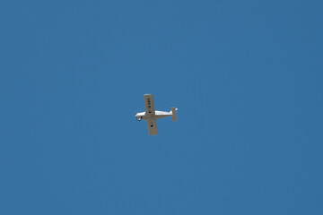 small white microlight plane in the sky with a bright blue sky in the background