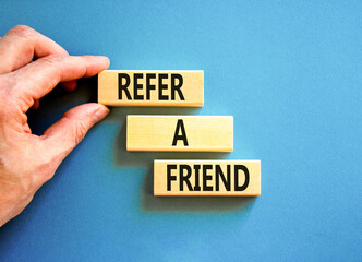 Refer a friend symbol. Concept words Refer a friend on wooden blocks on a beautiful blue table blue background. Businessman hand. Business and refer a friend concept. Copy space.