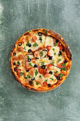 Delicious vegetarian tomato and cheese pizza with greens on a green stone background, Close-up top view