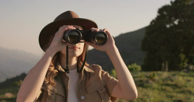 Woman forest watchman through binoculars monitors the safety of the forest, preventing fires. Young female forester watches her territory through binoculars. Fire watch. Woman watcher of the forest. 