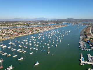 aerial shot of boats and yachts docked in the Newport Beach Harbor surrounded by blue ocean water,...
