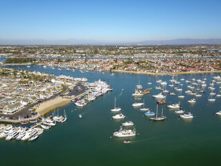 aerial shot of boats and yachts docked in the Newport Beach Harbor surrounded by blue ocean water,...