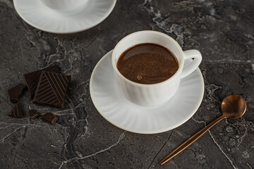 Soft focus. Hot chocolate in white porcelain cups with saucer on a stylish dark background. Hot coffee drink for the menu