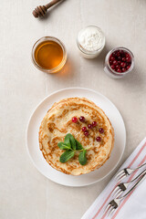 Stack of homemade pancakes served with honey and berries, top view