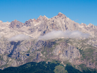 Altas montañas rocosas con algunas manchas de niebla y cielo azul.
