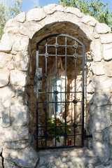 Small stone shrine with Virgin Mary holding hands in pray, a place of worship, in Biograd na moru, Croatia