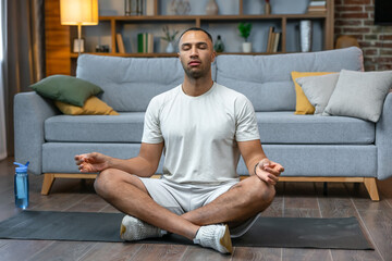 Fitness, meditation and healthy lifestyle concept - african american man meditating in lotus pose...