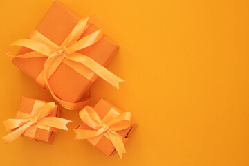 three orange gift boxes with a bow on an orange background. Space for text. top view