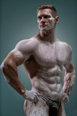 Fototapeta na wymiar White clay covers the naked torso of a muscular man