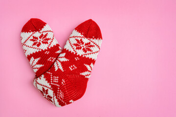 Knitted socks folded in the shape of heart on pink background. Valentine's day. Holiday background