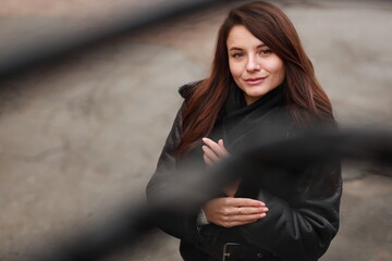 Beautiful young brunette woman in leather jacket outdoors