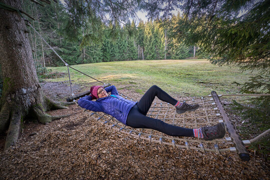 nice senior woman relaxing in a rustic hammock on a cold autumn day in the Allgaeu alps, Bavaria, Germany
