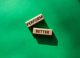 Perform better symbol. Wooden blocks with words Perform better. Beautiful green background. Business and Perform better concept. Copy space.