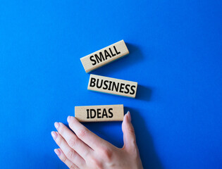 Small Business Ideas symbol. Wooden blocks with words Small Business Ideas. Businessman hand. Beautiful blue background. Business and Small Business Ideas concept. Copy space.