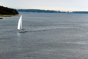 Weiter Panoramablick über die Kieler Förde mit einem Segelboot im Vordergrund, Küste,...
