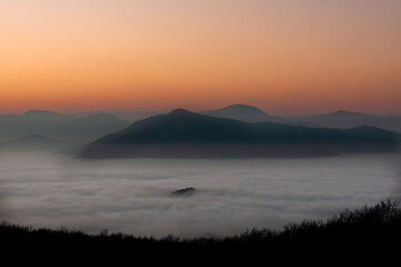 Tramonto tra nebbia e montagne