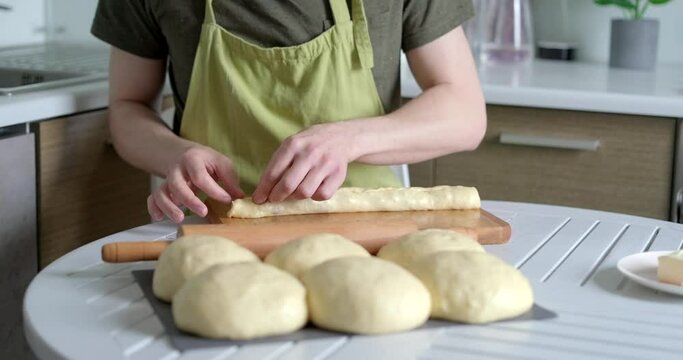 Homemade easter pastry cruffin preparation at home concept. Unrecognisable person pinching kneaded and rolled dough smeared with butter. High quality 4k video footage