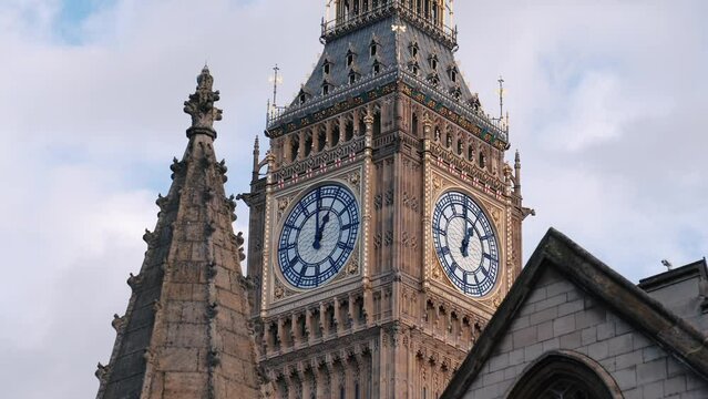 4K close up video with the landmark clock from Big Ben tower in London during a sunny day with blue sky and white clouds through Westminster Parliament