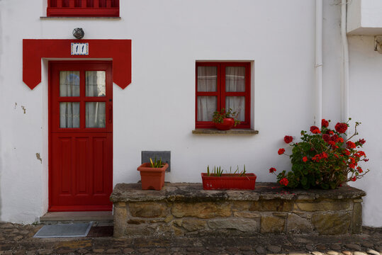 White house with red door and window and flowers 