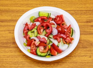 Fresh salad with tomato, cucumber, onion and green chili served in plate isolated on table top view of indian and pakistani spicy food