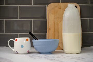 vegan breakfast milk almond, soy, oat milk alternatives to cows milk on breakfast cereal and cup of tea on marble worktop in kitchen