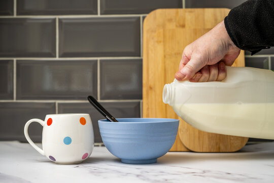 man pouring vegan oat soya almond or  coconut milk onto breakfast cereals in kitchen