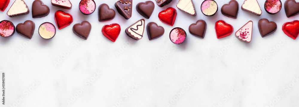 Poster valentines day chocolate top border. red and pink heart theme. overhead view on a white marble banne
