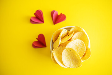 Yellow potato chips with salt and season on a yellow background