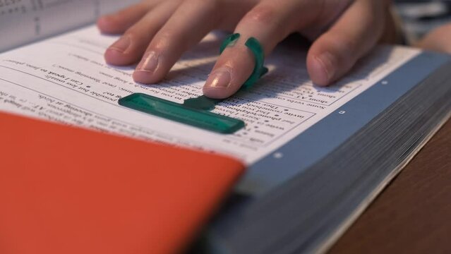 Reading tools for dyslexia. Child reading book using finger focus highlighter dyslexia tool. Education, learning disability, reading difficulties concept