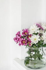 Vase with multi-colored chrysanthemums on the windowsill.