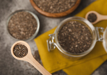 Chia seeds in a spoon and bowl on a black texture background.Superfood and axiontidant. Diet. Close-up. Place for text. Copy space.