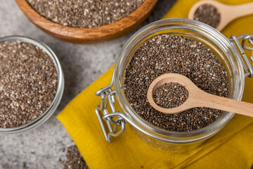 Chia seeds in a spoon and bowl on a black texture background.Superfood and axiontidant. Diet. Close-up. Place for text. Copy space.