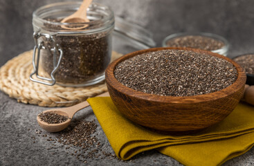 Chia seeds in a spoon and bowl on a black texture background.Superfood and axiontidant. Diet. Close-up. Place for text. Copy space.