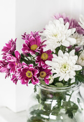 Obraz na płótnie Canvas Vase with multi-colored chrysanthemums on the windowsill closeup.