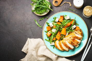 Chicken salad with pumpkin and arugula at black.