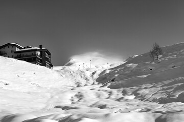 Black and white view on off-piste slope and hotel in winter mountains