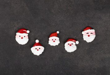 Christmas sweets. Candies in the shape of Santa Claus, covered with colored icing sugar. Dark background. Top view. New Year