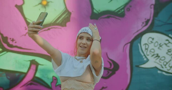 Redhead content creator woman taking videos in city against graffiti