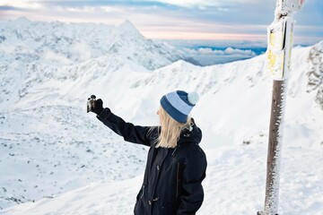 Woman photographs selphie on the Zawrat Pass in the Tatra Mountains in winter. Winter and sunrise...