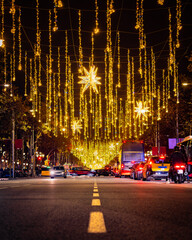 Yellow Christmas lights on over a boulevard at rush hour