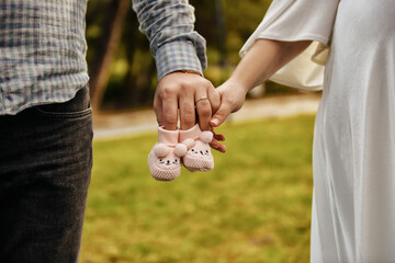 Pregnant Couple Holding Bootee Together 