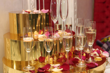 wine glasses with champagne and rose petal on table close up photo