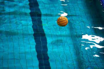Yellow water polo ball in a swimming pool on blue water background. Film noise and gain - 558486202