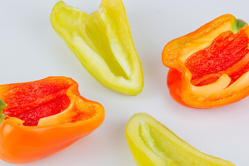 Halved green and red bell peppers isolated on white background. Cutting contour. View from above.