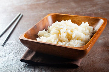 Boiled rice, cutlery and napkin on gray concrete background.