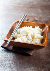 Boiled rice, cutlery and napkin on gray concrete background.