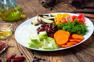 fresh vegetables: eggplants, beans, leek, tomatoes, chili peppers, carrot, garlic, onion on old...