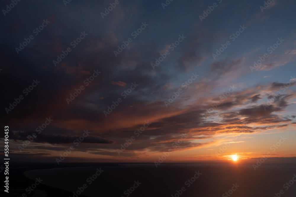 Poster the sun is setting over the ocean with clouds in the sky and the sun setting over the water in the d
