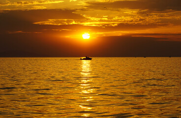 An intense orange sky above the shiny undulating surface of the sea at sunset at sea