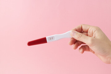 Positive pregnancy test on pink background